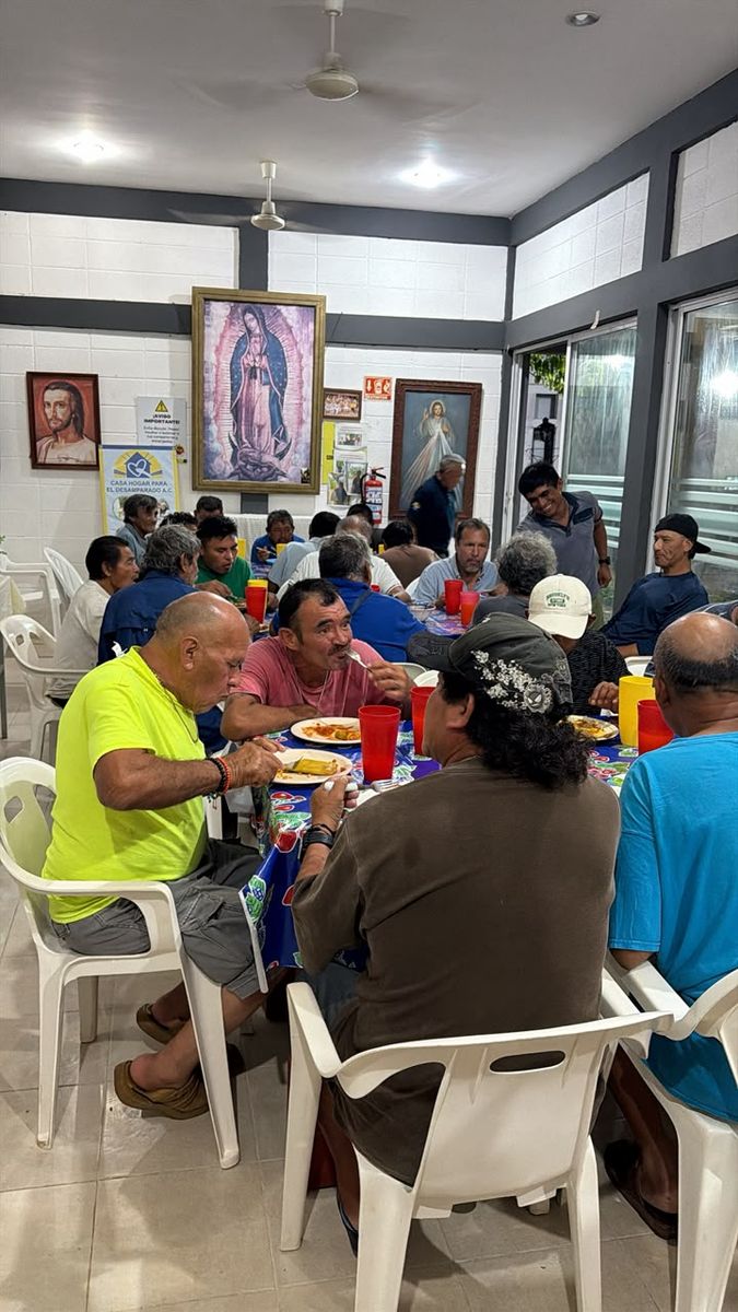 Cena compartida en el comedor de Casa Hogar El Samaritano, con mesas largas y una pintura de la Virgen de Guadalupe al fondo.