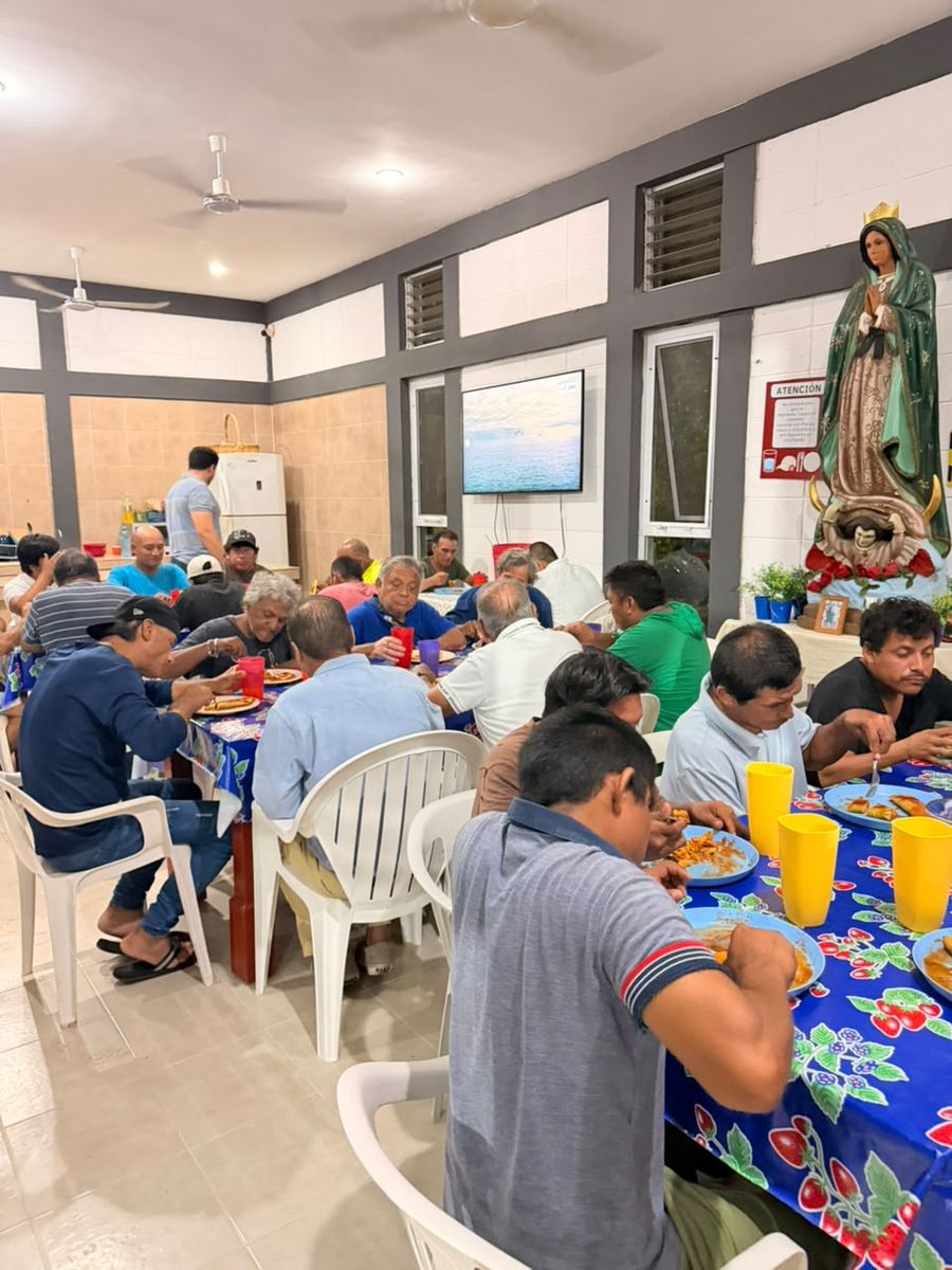 Mesas largas durante la cena, junto a una imagen de la Virgen de Guadalupe.